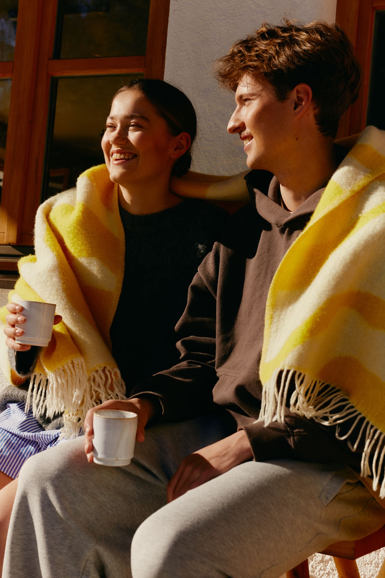 Two friends laughing on a couch under a blanket, the kind of moment Instagram posts get shared in