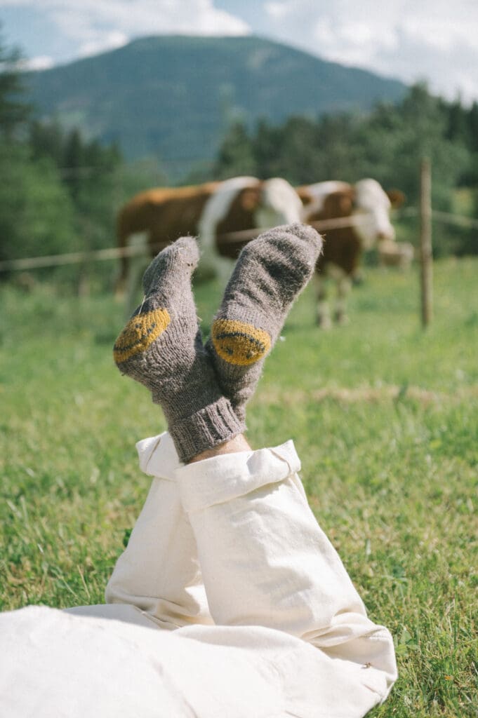 Feet in woolly socks up in a grassy field, taking a break from time on social media